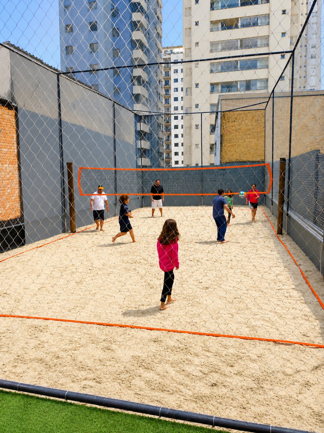 Famílias e estudantes jogando vôlei na quadra de areia